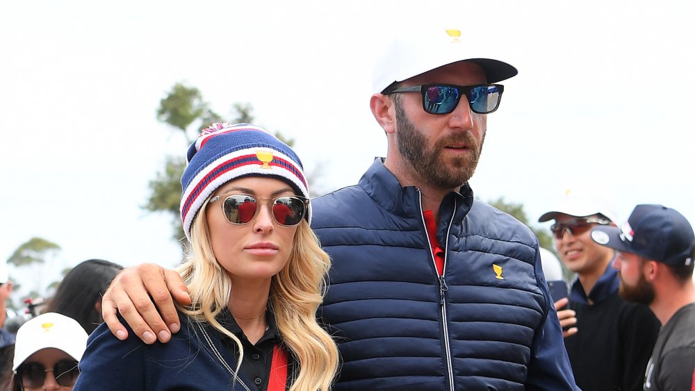 Dustin Johnson and Paulina Gretzky, wearing sunglasses while walking arm in arm