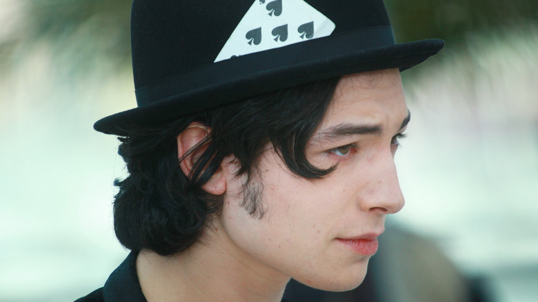 Ezra Miller with a card in their hat