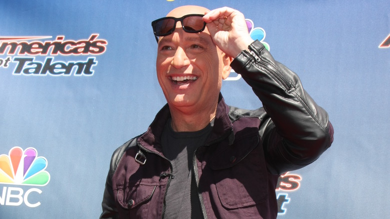 Howie Mandel smiling and adjusting shades