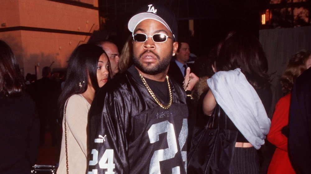 Ice Cube looking intensely at a photographer in sunglasses, a large chain, and Raiders gear
