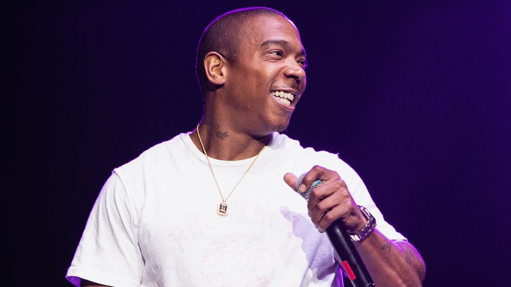 Ja Rule in a white t-shirt, holding a mic and smiling big during a concert