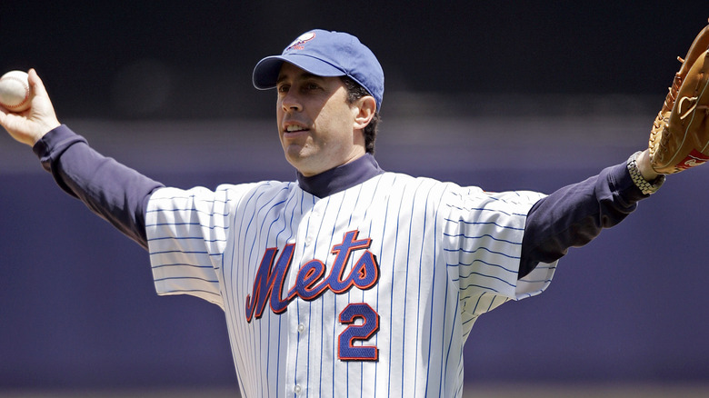 Jerry Seinfeld spreading his arms, wearing a Mets jersey and baseball glove