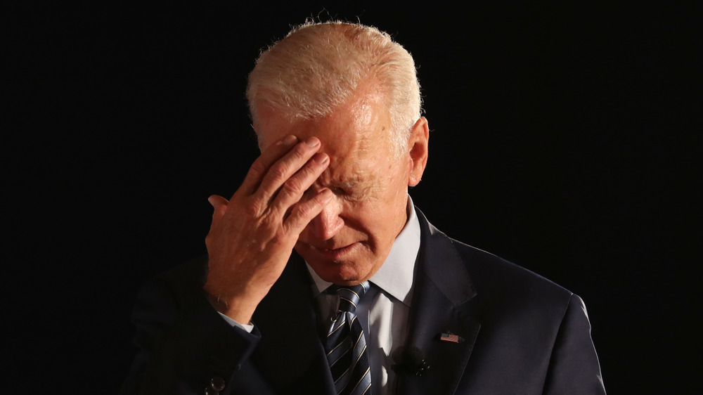 Joe Biden looking down, touching his forehead 