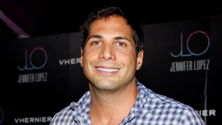 Joe Francis posing in front of a car