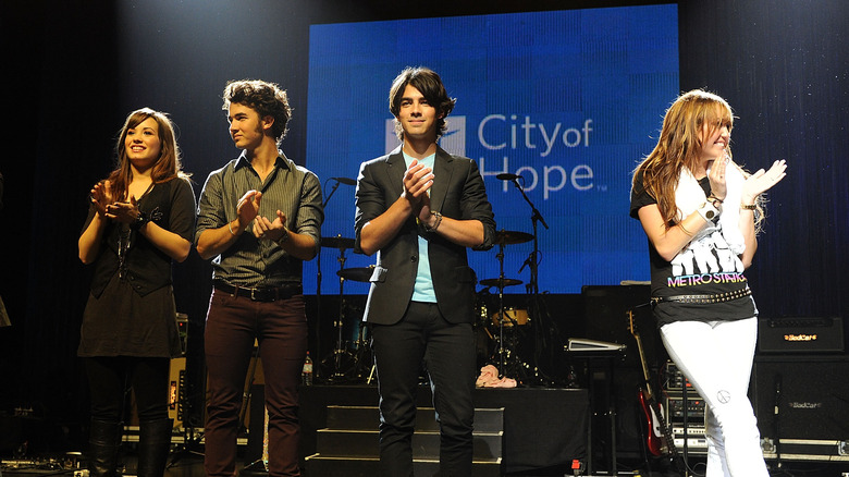 Demi Lovato, Kevin Jonas, Nick Jonas, and Miley Cyrus standing together