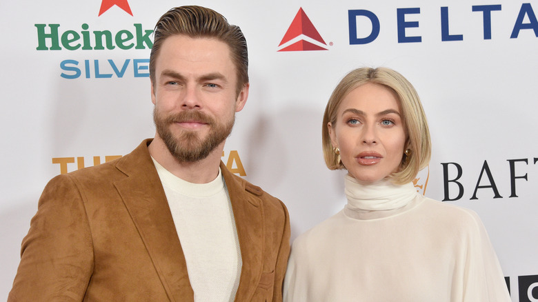 Derek Hough wearing a brown suede jacket and white shirt with Julianne Hough wearing a cream turtleneck