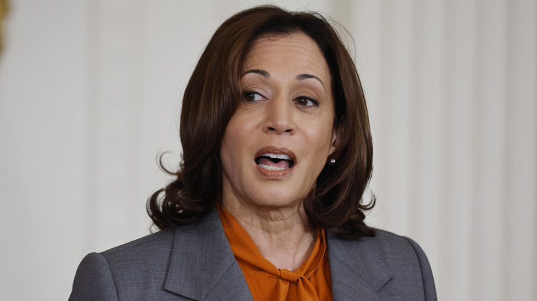 Kamala Harris speaking publicly in an orange blouse