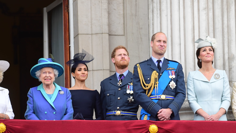 Queen Elizabeth, Meghan Markle, Prince Harry, Prince William, Kate Middleton smiling on a balcony 