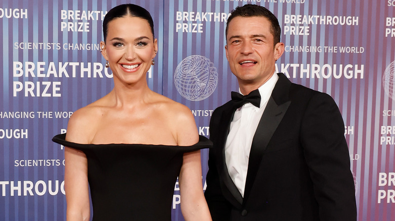 Katy Perry wearing a black gown and Orlando Bloom wearing a black tuxedo