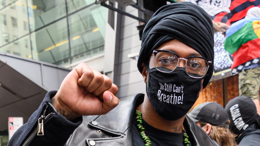 Nick Cannon wearing a face mask with the phrase "we still can't breathe"