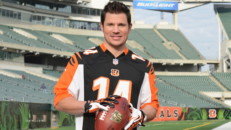 Nick Lachey wearing a Bengals jersey and holding a football