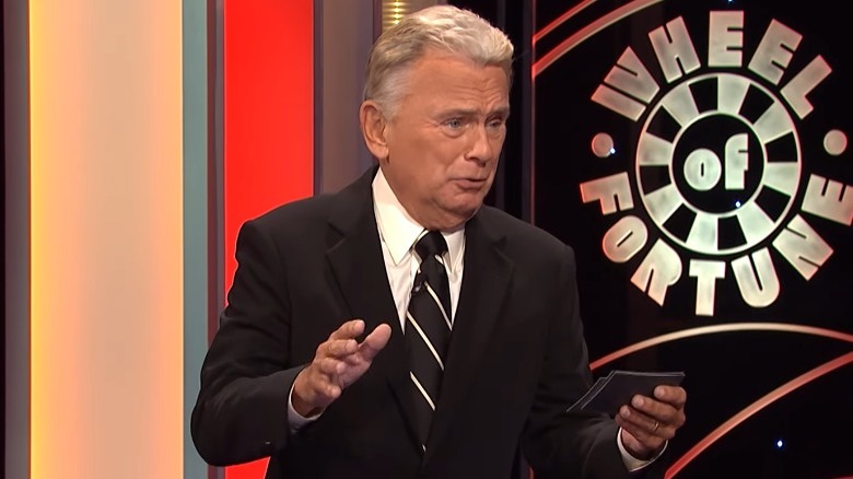 Pat Sajak speaking with a contestant on Wheel of Fortune