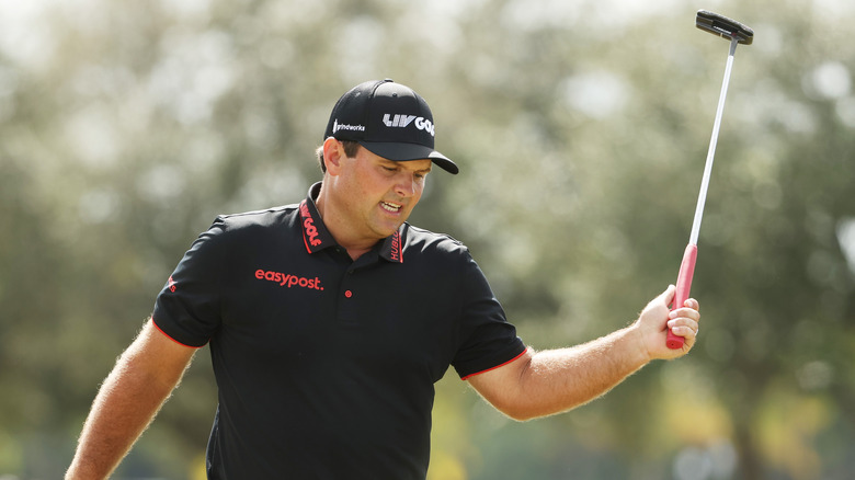 Patrick Reed, looking angry, swinging golf club