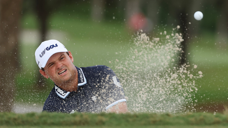 Patrick Reed swinging a ball in sand