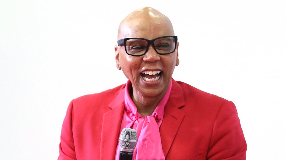 RuPaul laughing in red and pink outfit