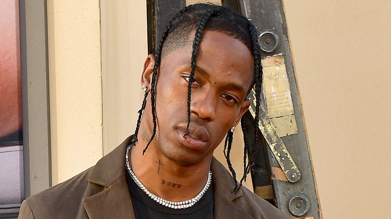 Travis Scott wearing a diamond necklace, looking at camera