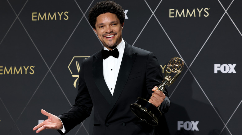 Trevor Noah smiling and holding Emmy award