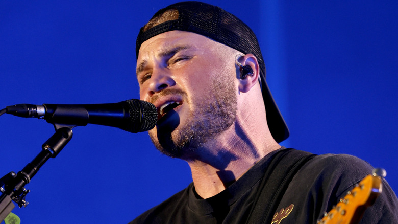 Zach Bryan on stage with a blue background