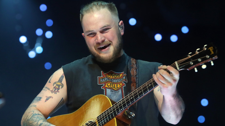 Zach Bryan playing guitar on stage