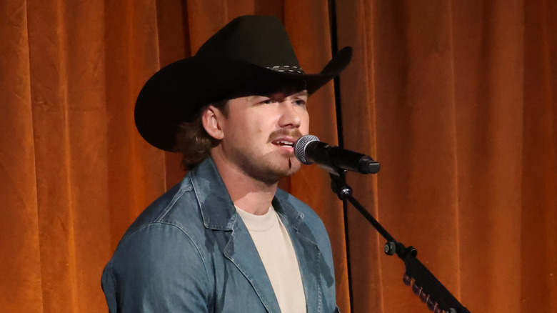 Morgan Wallen on stage with a curtain behind him