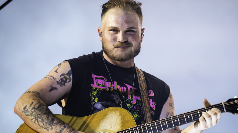 Zach Bryan on stage with a grey background