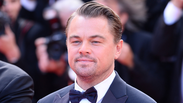 Leonardo DiCaprio smiles in front of yellow background