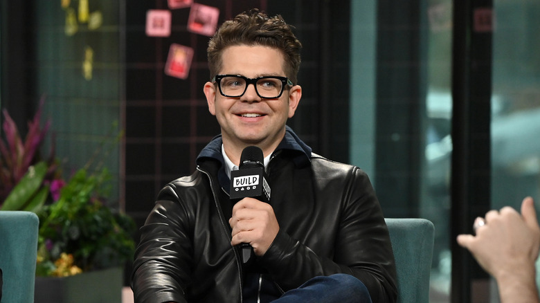 Jack Osbourne smiles holding a microphone