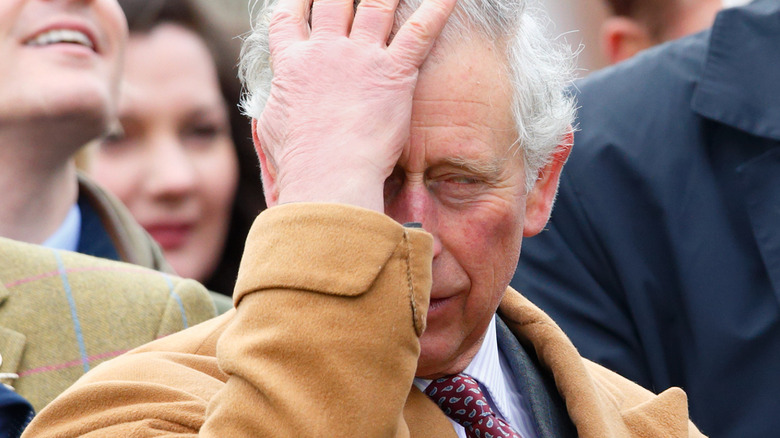 King Charles covers his face with his hand