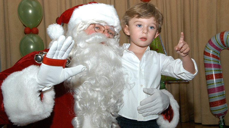 Person in Santa Claus costume waving, Barron Trump pointing