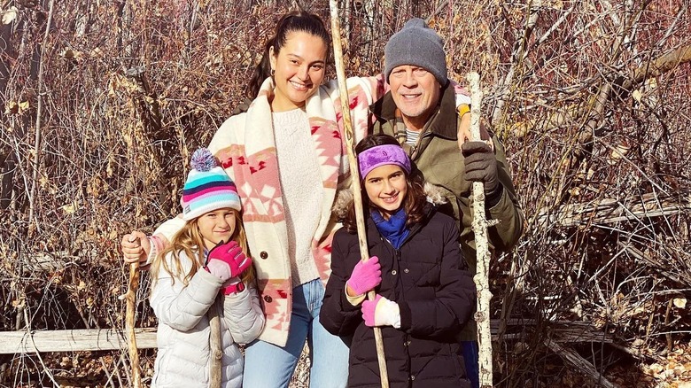 Emma with her kids and husband posing outdoors