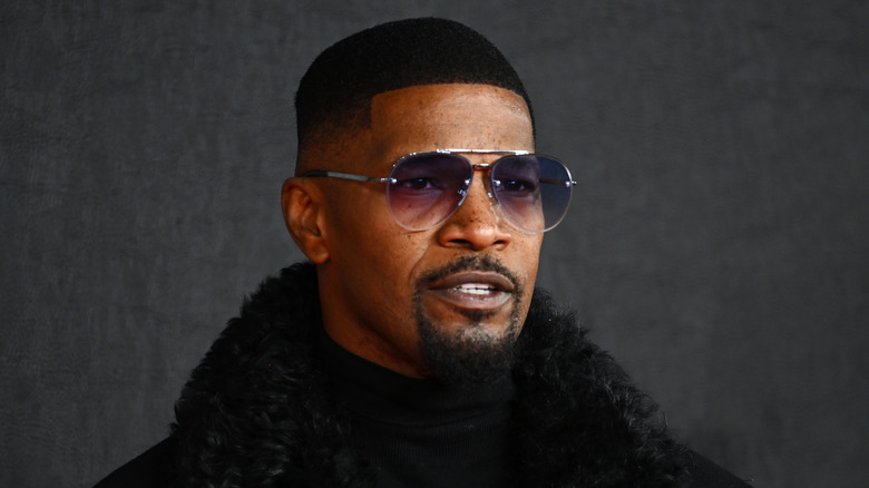 Jamie Foxx posing in sugnlasses and black coat