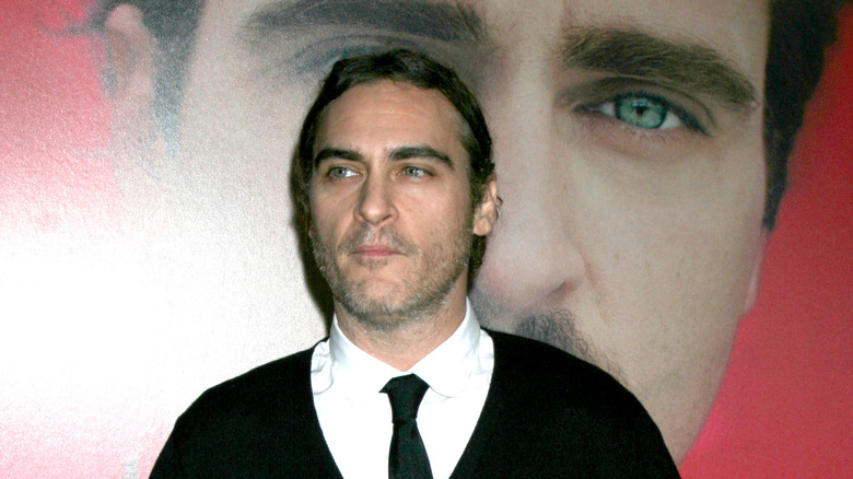 Joaquin Phoenix wearing a black sweater, white collared shirt, and black tie at Her premiere