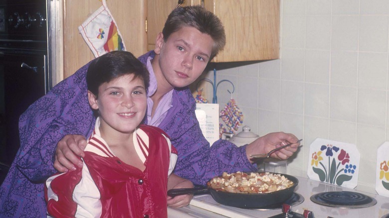 Young Joaquin Phoenix wearing a red and white jacket with River Phoenix wearing a purple jacket