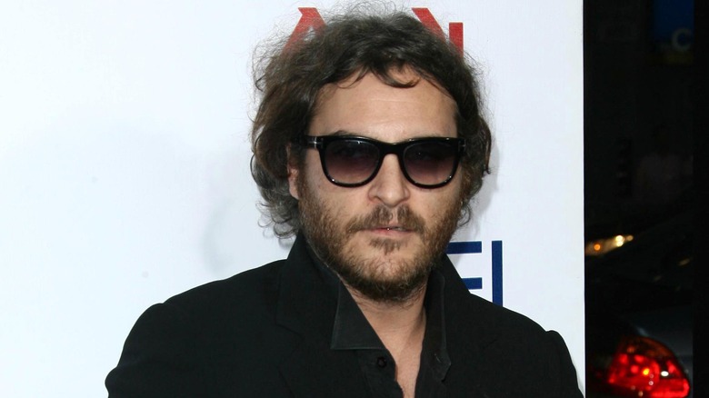 Joaquin Phoenix wearing black sunglasses and a black jacket