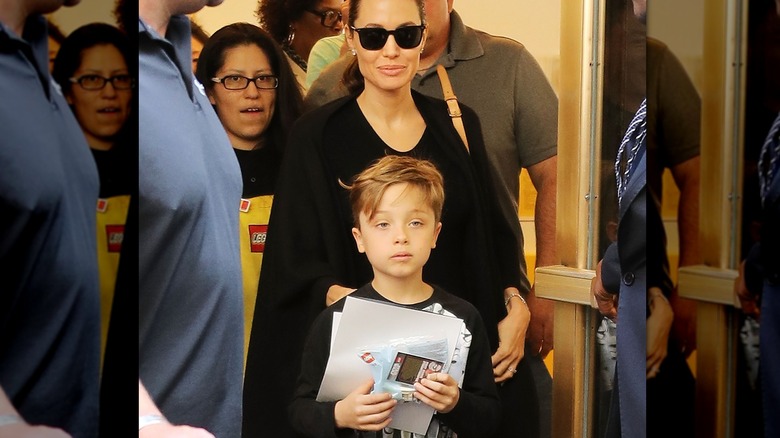 Knox Jolie-Pitt standing in front of mom Angelina Jolie