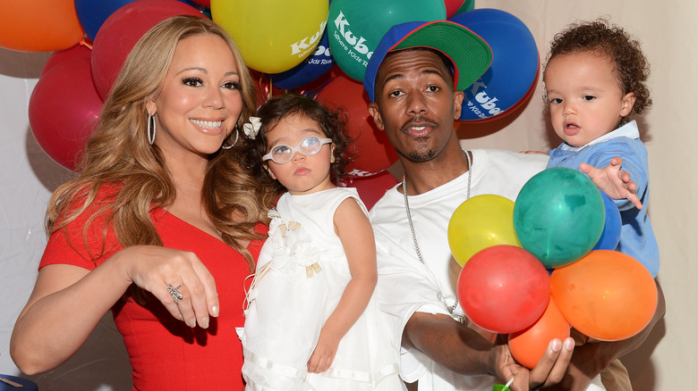 Mariah Carey, Nick Cannon, and their kids posing together in front of colorful balloons