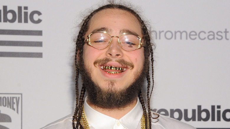 Post Malone smiling with gold teeth