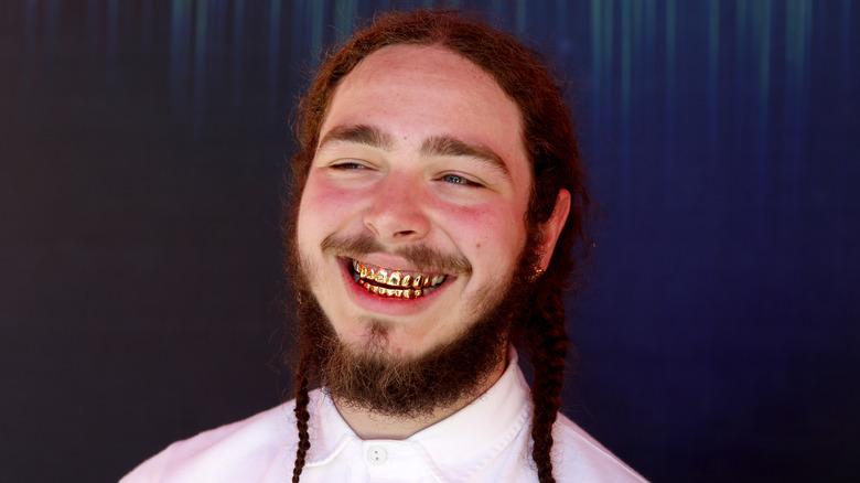 Post Malone smiling with gold teeth