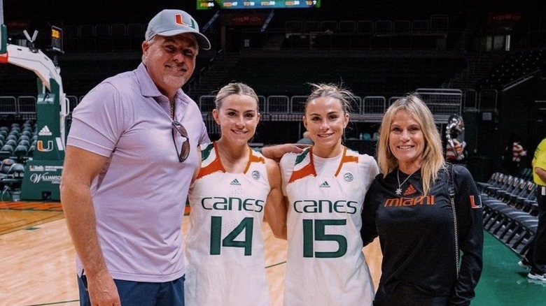 The Cavinder twins in their Miami uniforms smiling next to their parents.