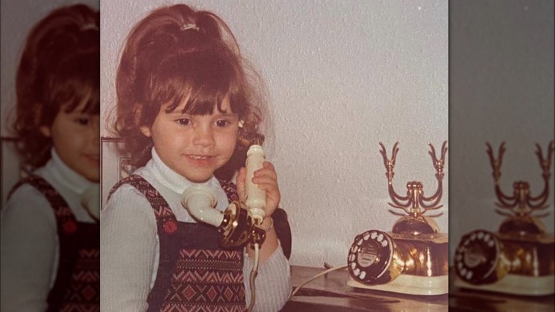 Child Victoria Beckham holding a phone