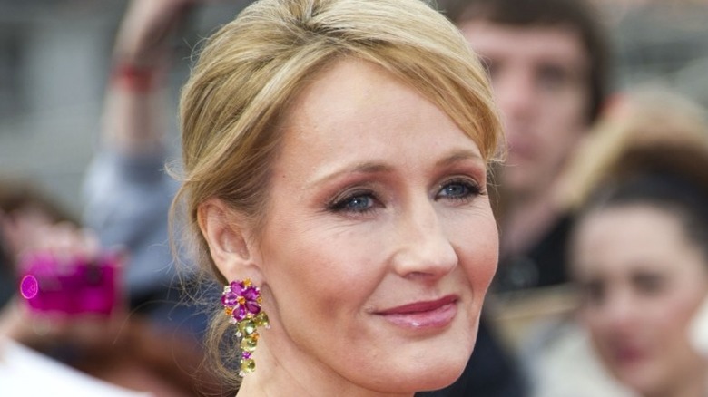JK Rowling smiling in pink and green earrings