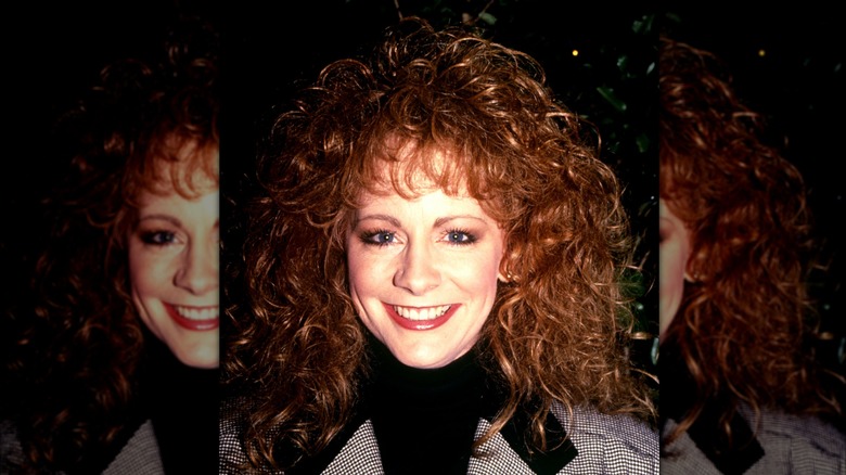 Reba McEntire in July 1996 with big red hair and a turtleneck