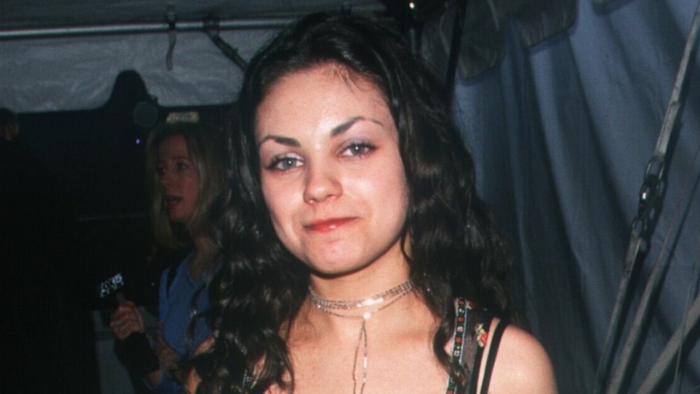 Mila Kunis in a black printed dress, posing at an event, in 2000