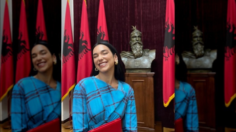 Dua Lipa in front of Albanian flags