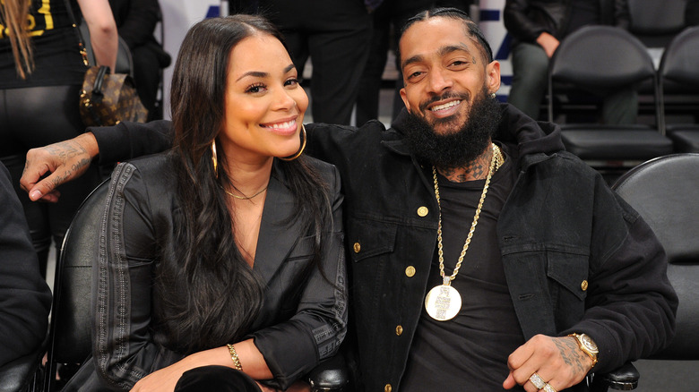 Lauren London and Nipsey Hussle smiling at basketball game