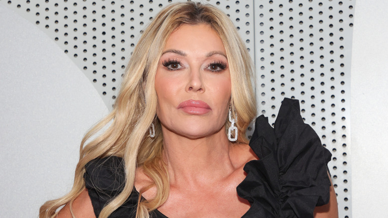 Brandi Glanville poses in black dress with ruffled sleeves.