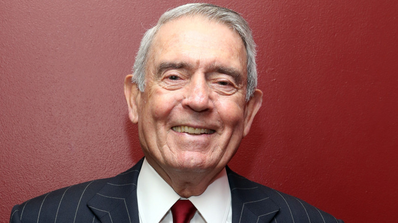 Dan Rather smiles against a red wall