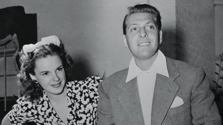 Judy Garland, clad in a floral-print dress, stands next to David Rose