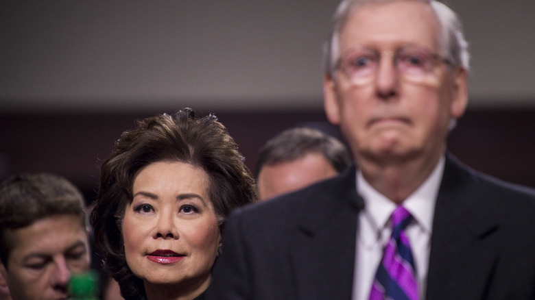 Elaine Chao stands near Mitch McConnell looking glum