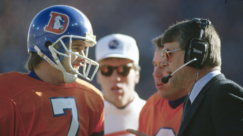 1988 Head Coach Dan Reeves of the Denver Broncos talks with his quarterback John Elway #7 